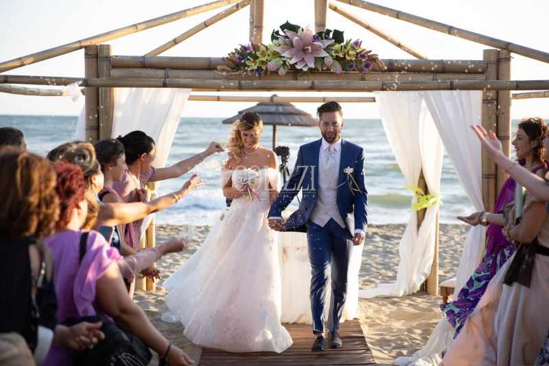 coppia di sposi riva al mare giorno matrimonio spiaggia invitati