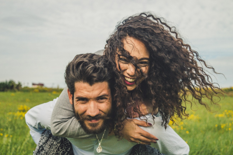 giovane donna capelli ricci sorridente sulle spalle uomo attraente barba