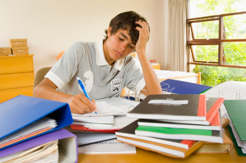 ragazzo scrive per fare i compiti a casa annoiato
