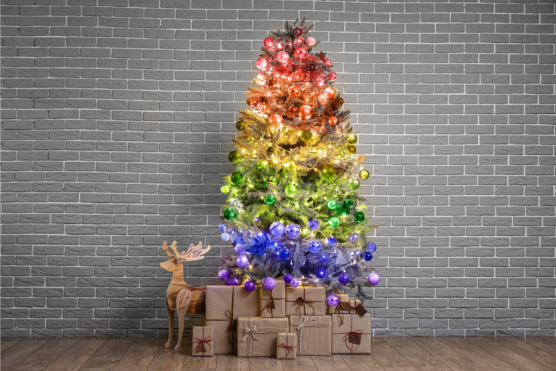 albero di Natale multi color pacchi regali su parquet renna di legno colori a spirale decorazioni viola blu verde giallo arancione