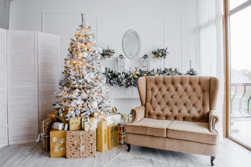 angolo natalizio soggiorno casa albero di Natale rami innevati luci oro pacchi regalo