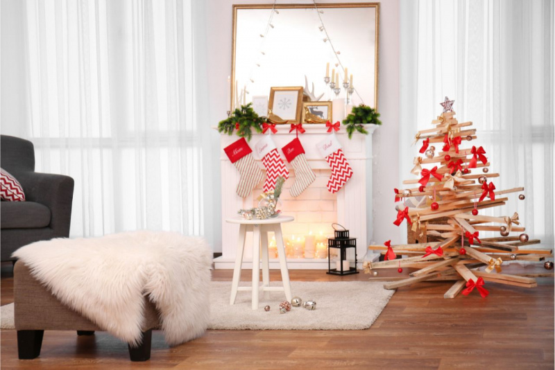 decorazioni natalizie divano specchio su camino rami calze bianco rosse sgabello legno albero di Natale alternativo