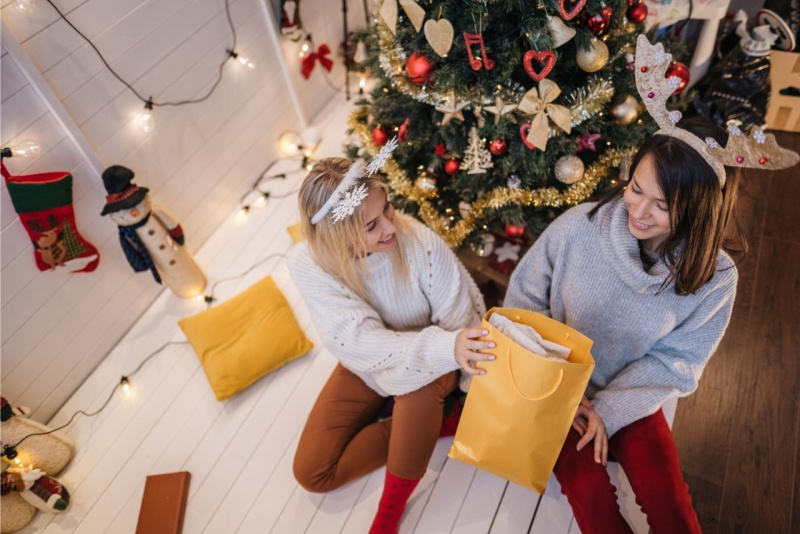 scambio doni regali natale tra amiche davanti albero di natale luci