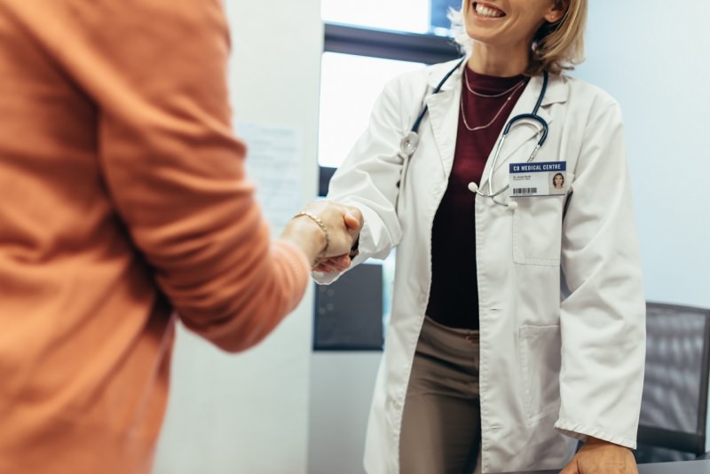 amichevole sorridente dottore stringe mano donna paziente