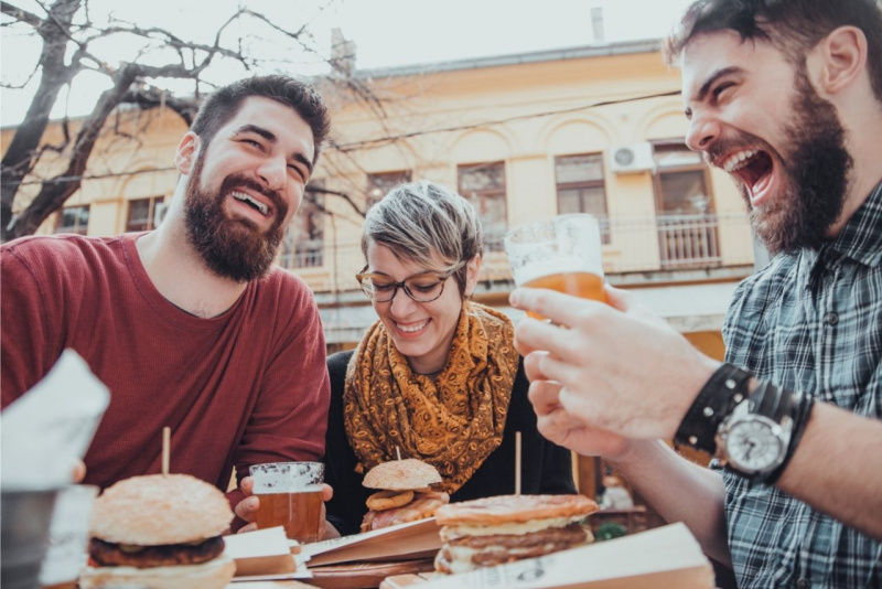 amici uomo donna mangiano hamburger fast food risate sorrisi bicchieri birra