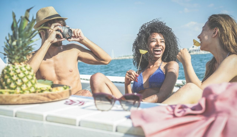 uomo con macchina fotografica barca mare ragazze mangiano frutta sulla barca estate abbornzatura