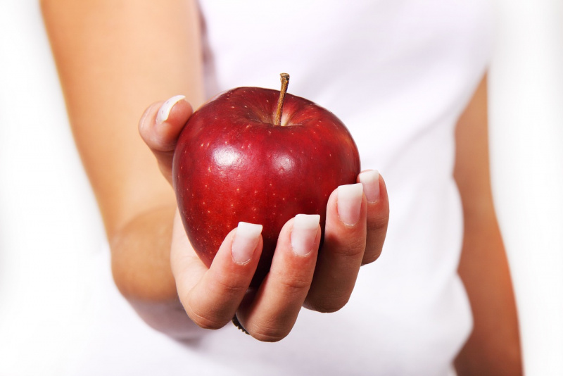 mela rossa in mano donna unghie curate naturali dieta