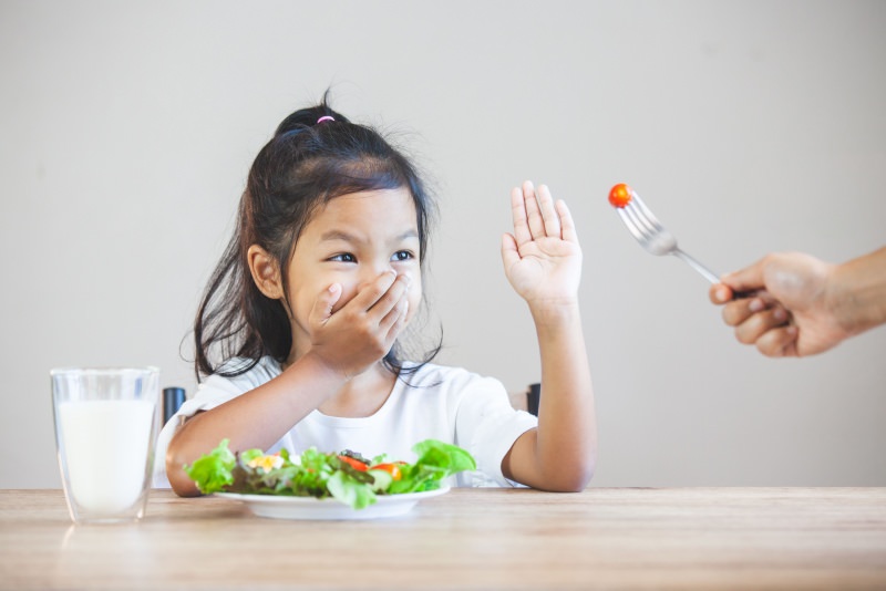 bambina non vuole mangiare verdure mano alzata stop forchetta pomodoro