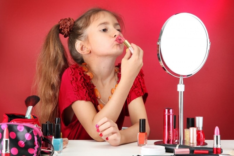 bambina si trucca allo specchio makeu rossetto