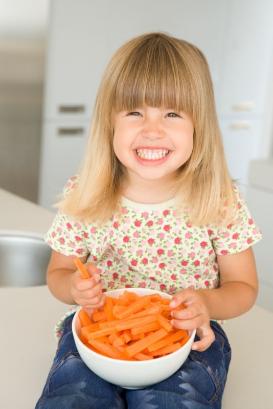 bambina sorriso tiene in mano ciotola di carote