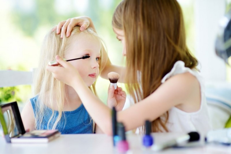 bambina mette mascara makeup alla sua amichetta gioco