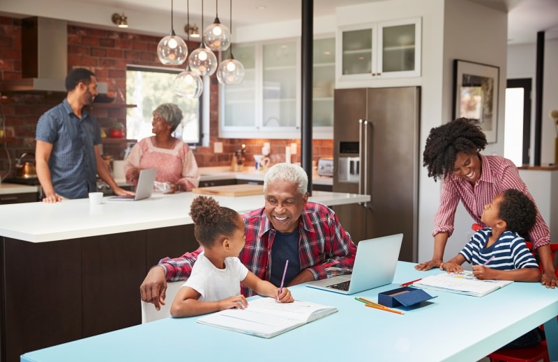 famiglia sta insieme a casa in cucina con notebook e bambini fanno i compiti