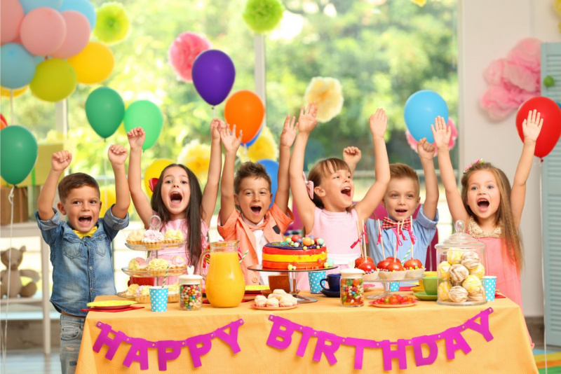 festa di compleanno palloncini colorati bambine bambini tavola dolci torta brocca succo arancia caramelle