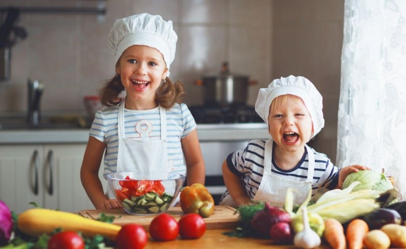 bambini con cappello chef sorrisi preparazione verdure cucina