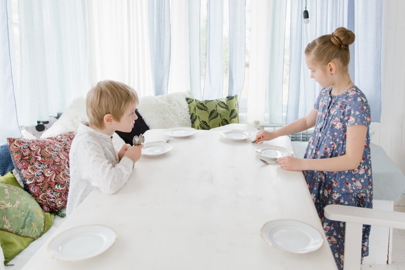 bambini mettono piatti sul tavolo apparecchiano