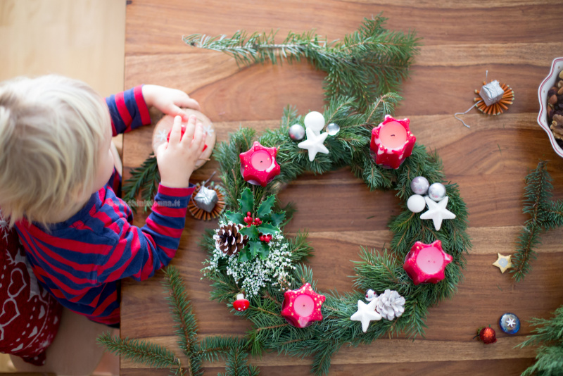 creare corona Avvento con i bambini tavola legno rami verde candele bambino piccolo