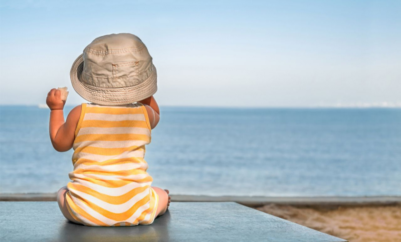 body di cotone giallo bianco beb primi mesi cappello cotone seduto davanti al mare