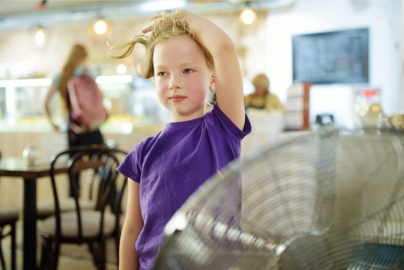 piccola bambina bionda sente caldo davanti ventilatore aria fresca in casa