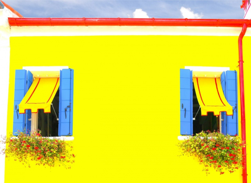 prospetto casa giallo finestre aperte con tende da sole estate