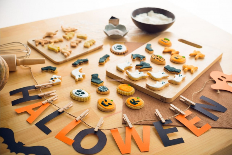 tavola con tagliere legno frusta biscotti mattarello pinze per abiti decorazioni scritta Halloween