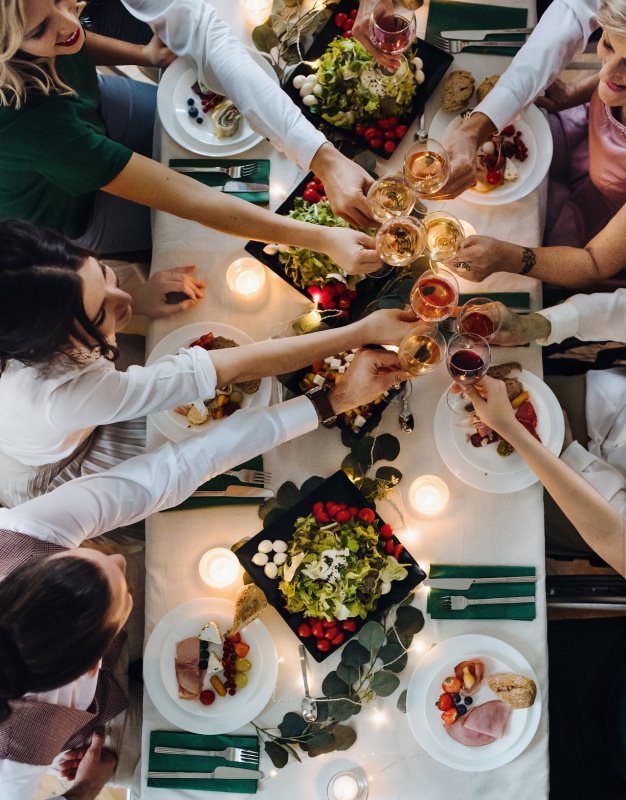 cena in compagnia sorrisi brindisi tavola apparecchiata amici famiglia tavolo visto dall'alto 