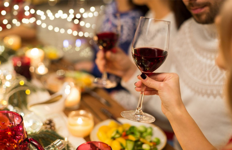 mano donna tiene calice vino rosso tavola apparecchiata brindare festa