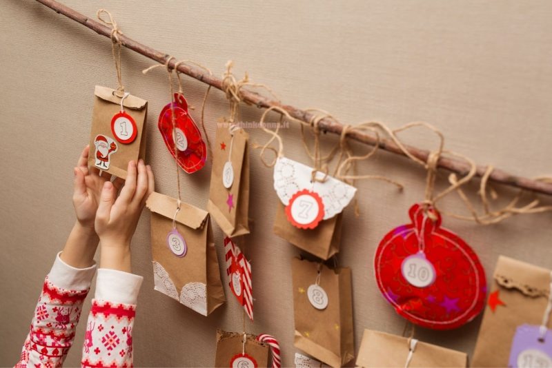 calendario dell'avvento natale sacchetti appesi con spago su ramo mani di bambino