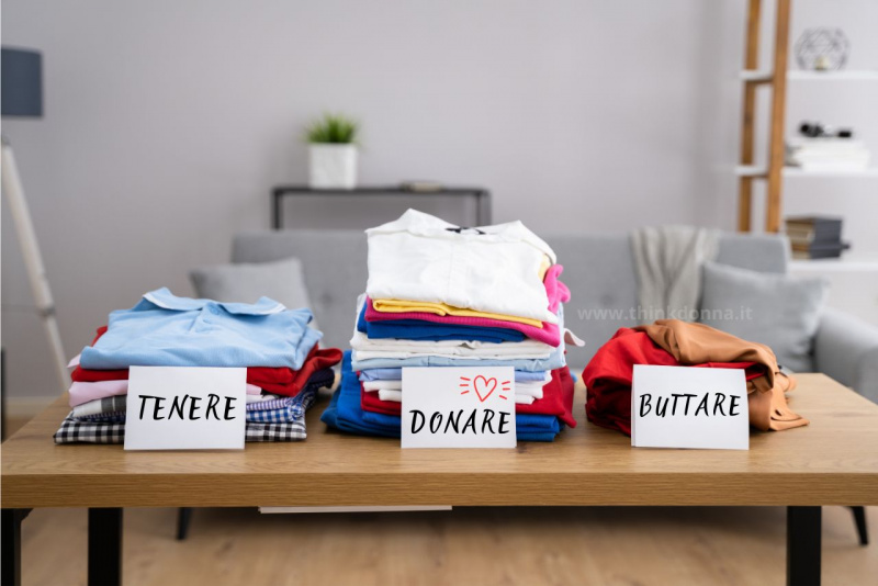 decluttering abiti su tavolo da tenere donare e buttare pulizia