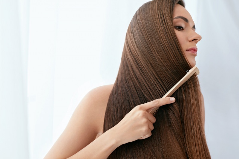 donna capelli lunghi lisci castani si pettina con pettine legno