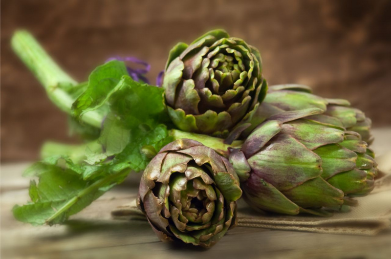 tre carciofi su tavolo legno