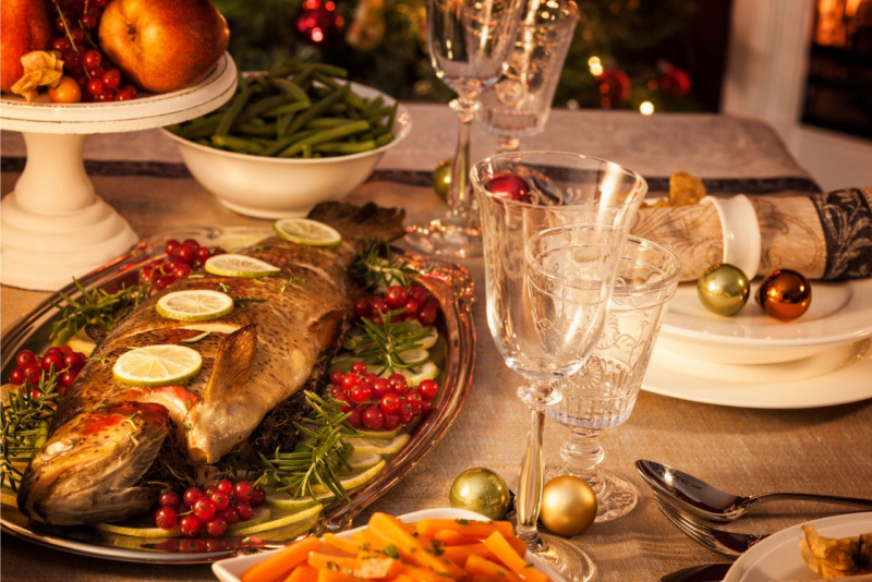 vassoio di portata con pesce fette limone alzatina frutta di stagione ciotola fagiolini verdi decorazioni natalizie tavola festa