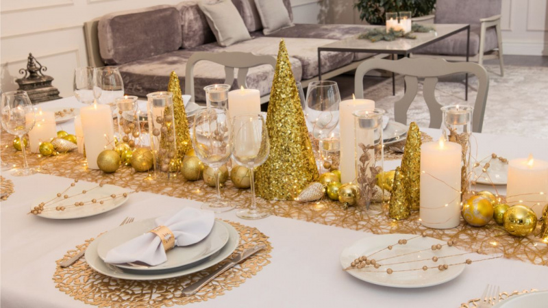 tavola apparecchiata cena festa Natale piatti porcellana bianca portatovagliolo anello oro candele divano velluto grigio