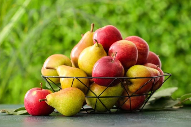 cesta ferro battuto piena di mele e pere su tavolo