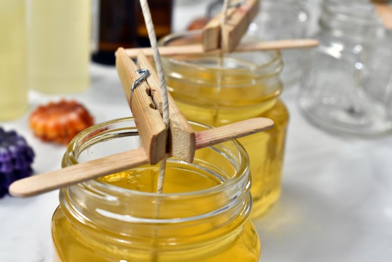 vaso di vetro con cera liquida stoppino candela pinza di legno