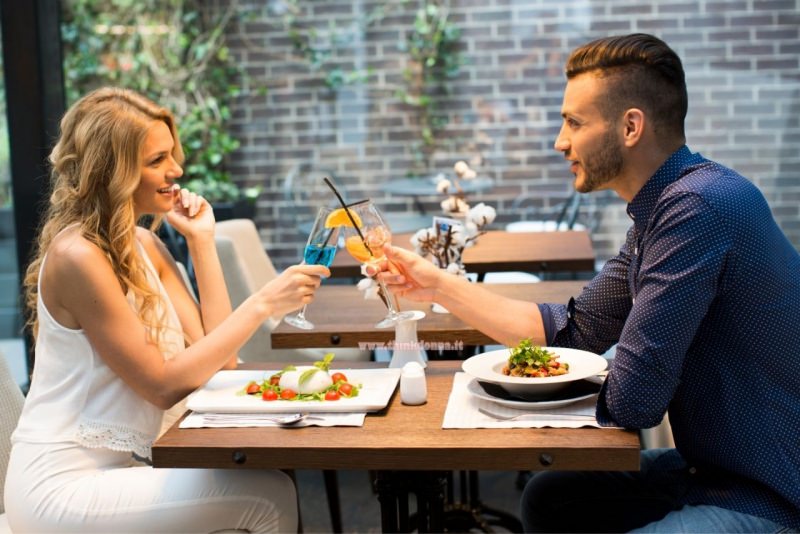 donna e uomo al primo appuntamento bar brindano drink incontro coppia