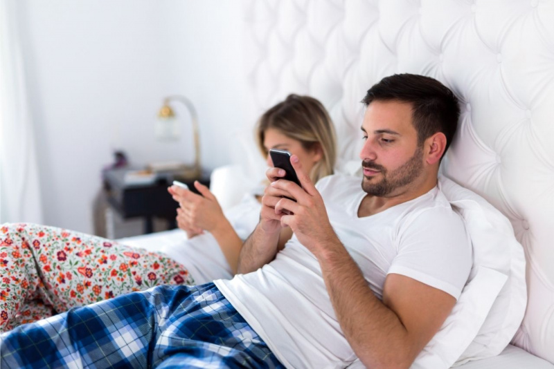 crisi di coppia uomo donna annoiati usano smartphone a letto 