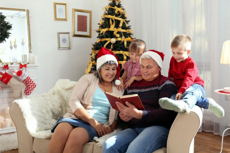 tempo di lettura con i bambini i nipoti nonni seduti sul divano leggono libro