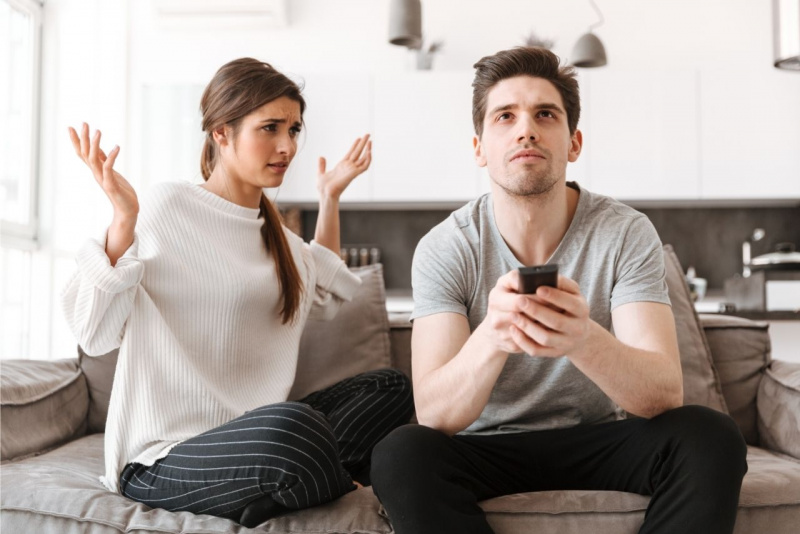 giovane donna non sopporta il compagno partner che fa zapping telecomando sul divano