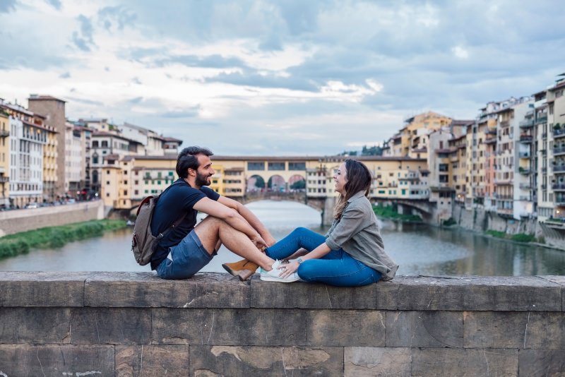 coppia innamorati uomo donna seduti davanti ponte vecchio firenze arno fiume