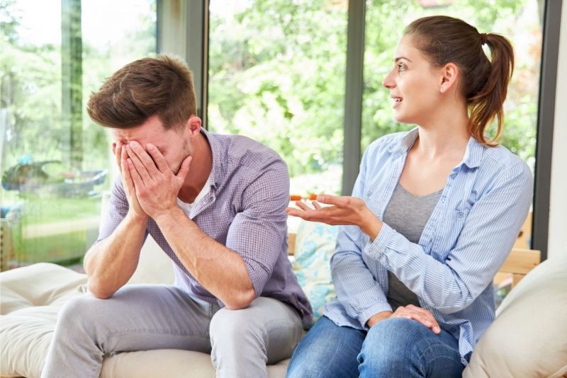 coppia uomo donna seduti sul divano discutono