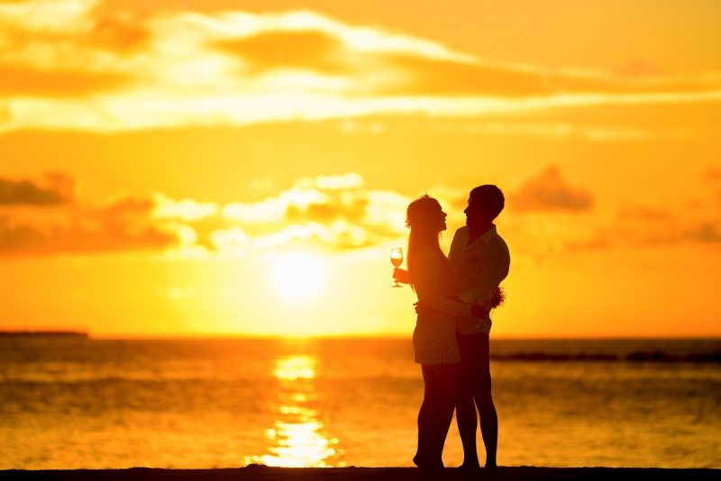 coppia innamorati abbracciati tramonto sole sul mare calice vino