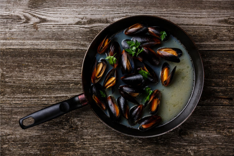 cottura cozze in padella su tavola legno