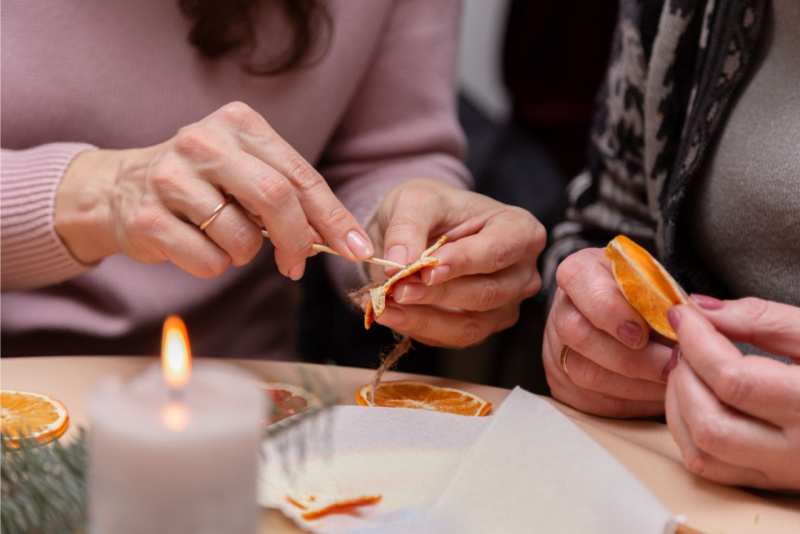 mani donna fanno un foro fetta arancia essiccata con stecchino di legno lavoretto hobby natale
