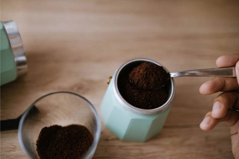 caff in polvere versato con cucchiaino nel filtro caffettiera moka