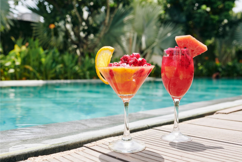 bicchieri da cocktail di vetro con smoothie frutti rossi fetta limone anguria estate in piscina