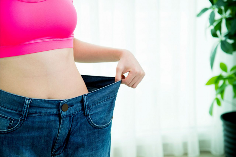 mano donna tengono jeans larghi dopo perdita peso dimagrire
