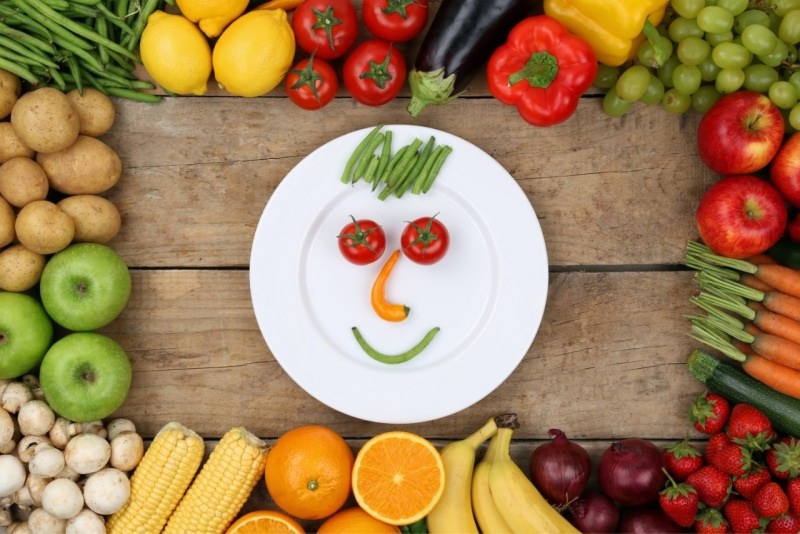 idee divertenti con cibo sorriso fatto con verdure su piatto pomodori carote limoni fagioline patate mela