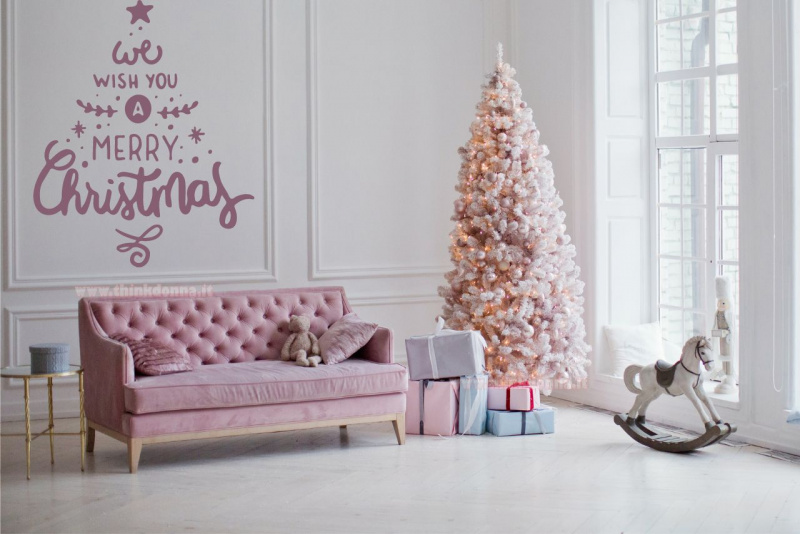 scritta we wish you a merry christmas a forma di albero con le lettere divano e albero di Natale rosa davanti finestra soggiorno 