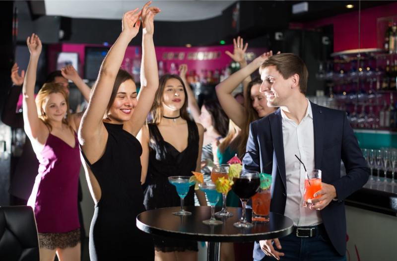 giovani donne ridono e si divertono al bar con uomo elegante completo giacca jeans