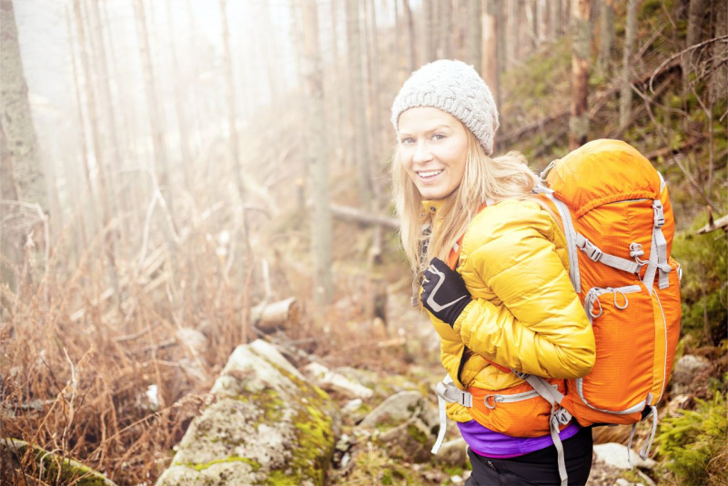 donna sorridente capelli biondi berreto di lana trekking alberi foresta bosco natura